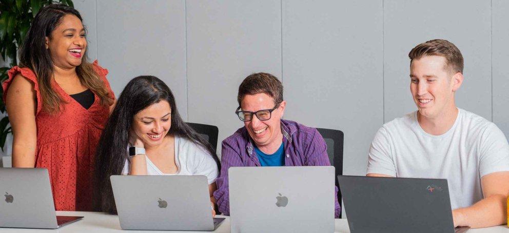 Students laughing studying in front of laptops