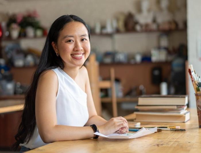 Gabrielle Ly at desk with paint brushes